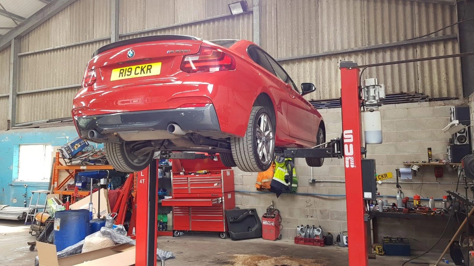 Red car raised on a vehicle lift at Rhodes Auto Centre